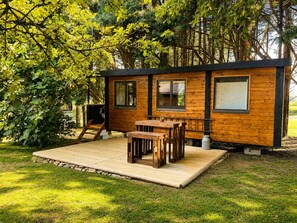 Une cabane en bois avec une terrasse, une table et des chaises.