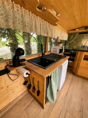 A compact kitchen with a sink, coffee maker, and a small refrigerator.