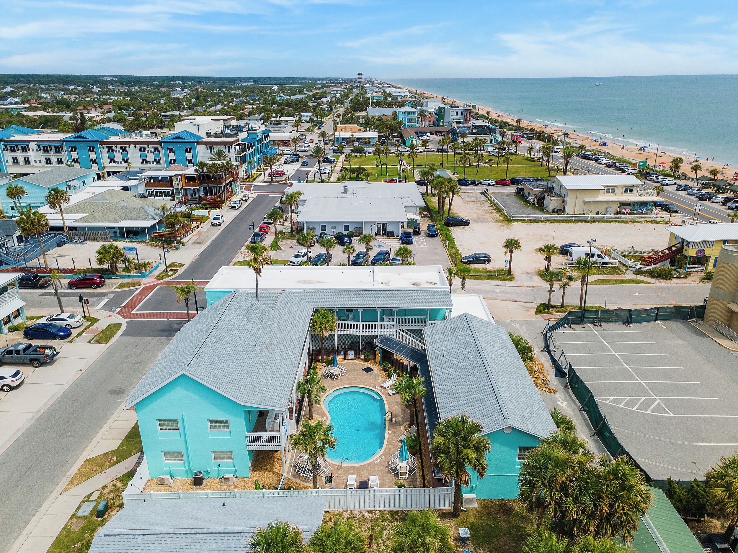 A coastal hotel with a swimming pool, multiple-story buildings, and a beach view.