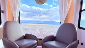 Dos sillones de cuero enfrentados, con vista a un paisaje desértico a través de una ventana.