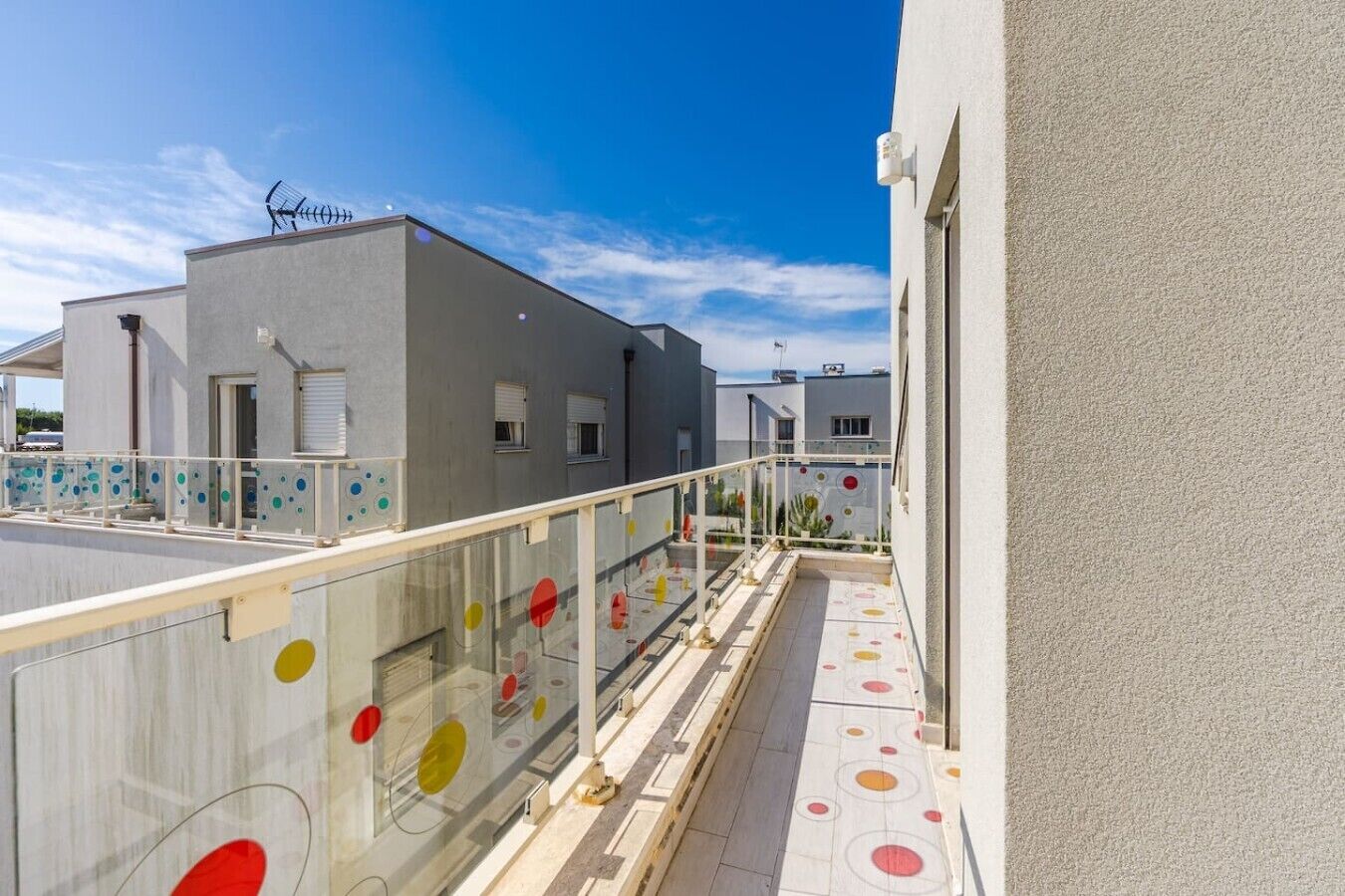 A modern building with a balcony, a clear sky, and a flat roof.