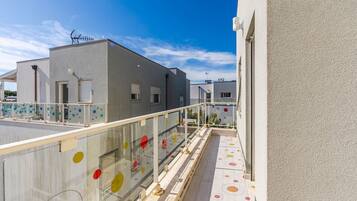 A modern building with a balcony, a clear sky, and a flat roof.