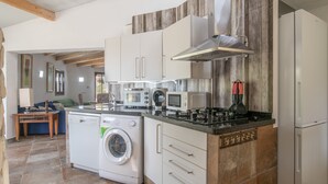 Une cuisine compacte dotée d’appareils électroménagers intégrés, d’un lave-linge et d’un coin repas avec une table et des chaises.
