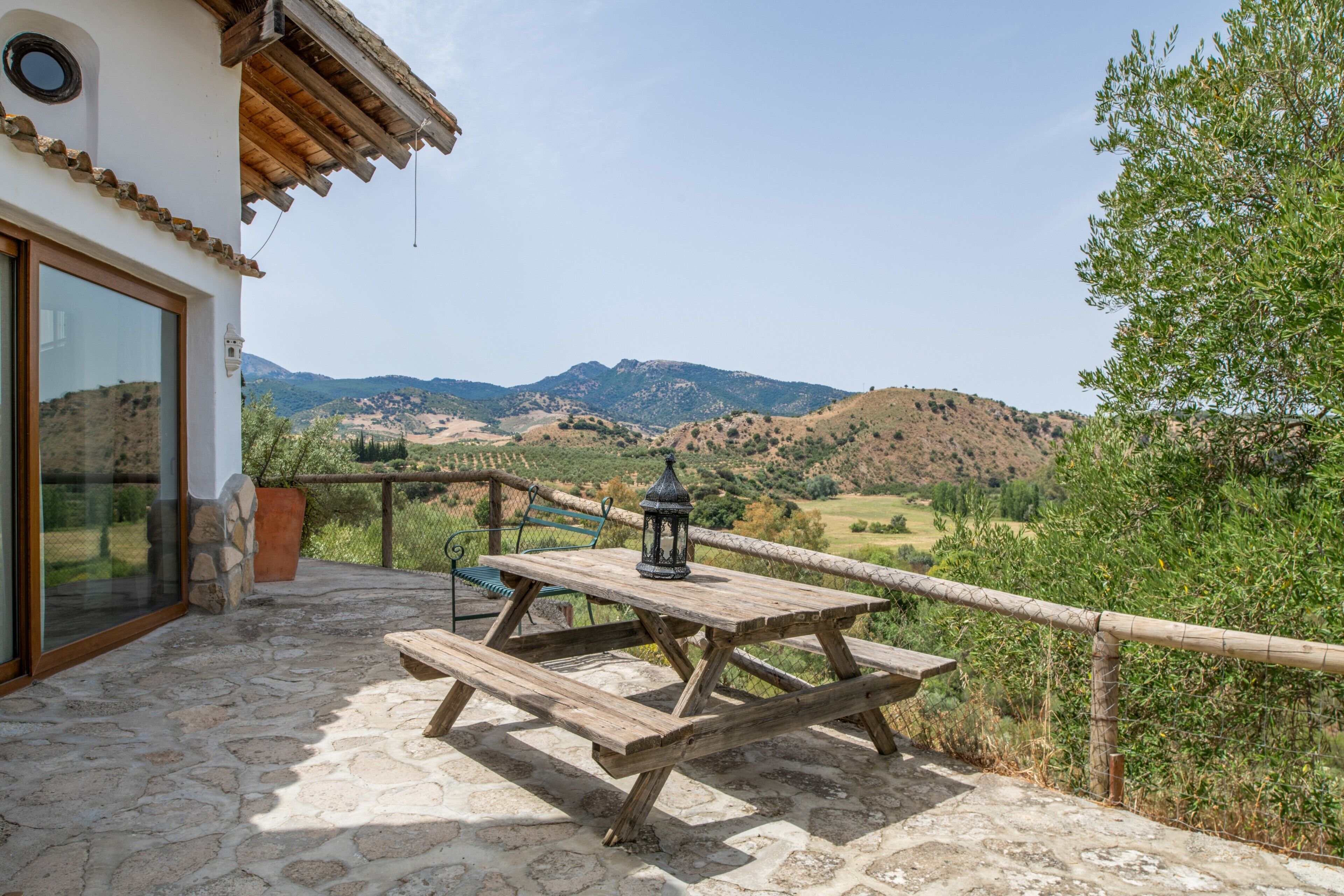 Un patio con una mesa y banco de madera, con vista a un paisaje montañoso.
