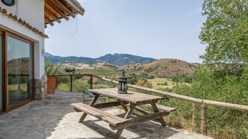Un patio con una mesa y banco de madera, con vista a un paisaje montañoso.