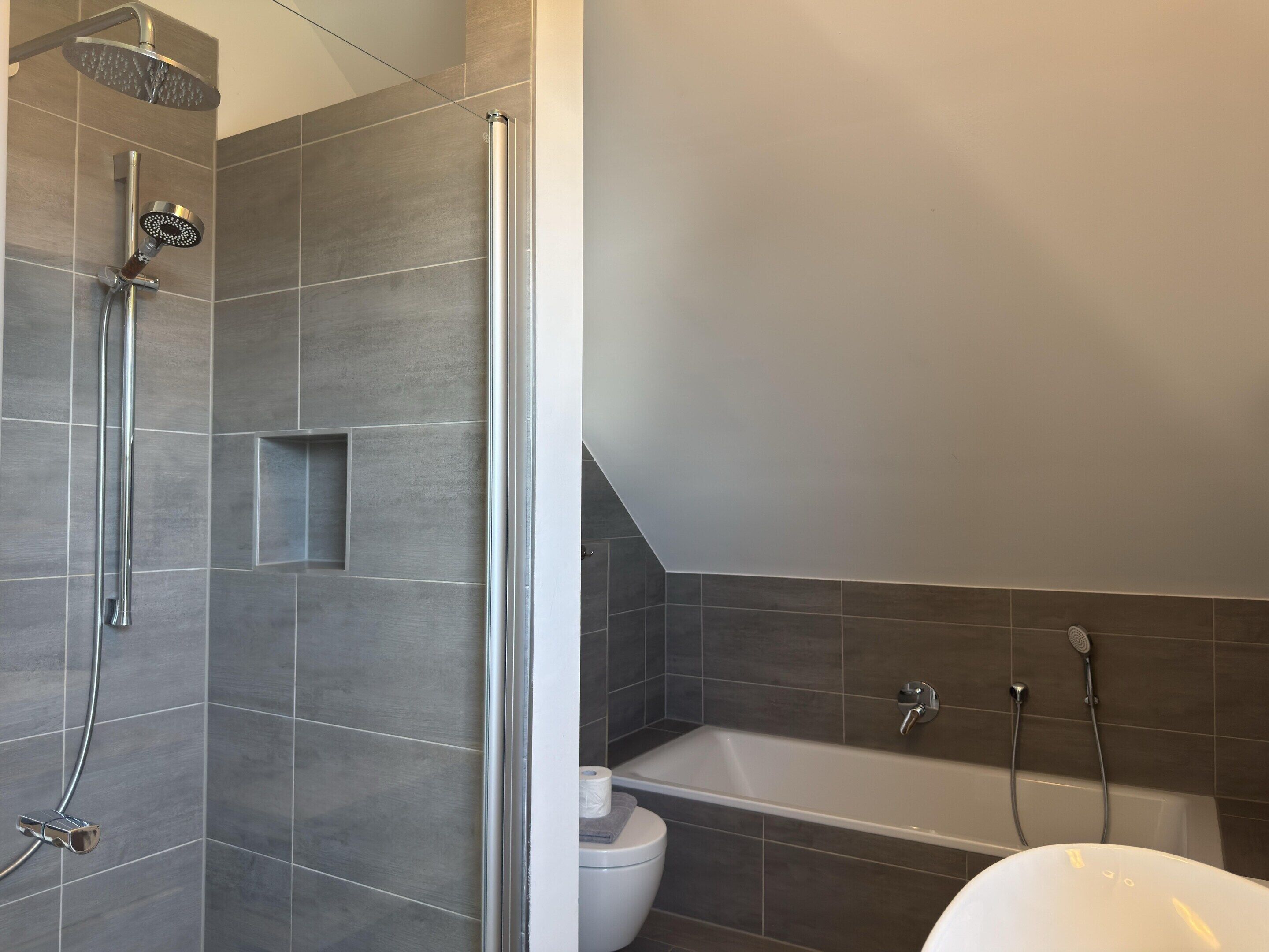 A modern bathroom with a shower, toilet, and bathtub.