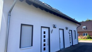 Un edificio con fachada blanca, varias puertas y ventanas con contraventanas.