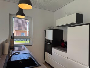 Eine moderne Küche mit Backofen, Spüle und Fenster mit Blick auf ein Backsteingebäude.