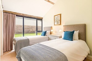 A hotel room with two beds, a window with curtains, a nightstand with lamps, and a framed picture on the wall. - Shippon 2 - with parking (Oxfordshire)