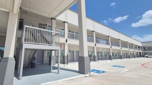 A multi-story building with a covered entrance, a parking lot with handicapped parking, and a 'NOW OPEN' sign. - Platinum Inn Copperfield (Houston)