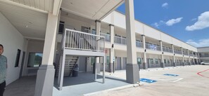 A multi-story building with a covered entrance, a parking lot with handicapped parking, and a 'NOW OPEN' sign.