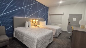 A hotel room with two beds, a sofa, a desk, and a bathroom door. - Platinum Inn Copperfield (Houston)