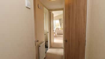 Ein schmaler Flur mit Heizkörper, einer Holztür und einer Leuchte an der Decke.