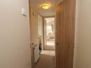 Ein schmaler Flur mit Heizkörper, einer Holztür und einer Leuchte an der Decke.