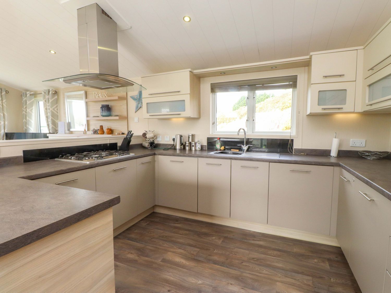 Een moderne keuken met een centraal eiland, inbouwapparatuur en een groot raam voor natuurlijk licht.