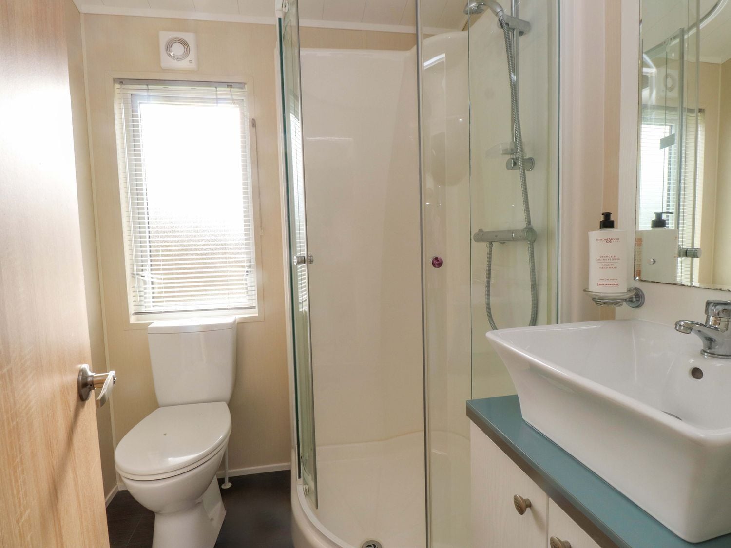 A bathroom with a toilet, a glass-enclosed shower, and a sink with a mirror.