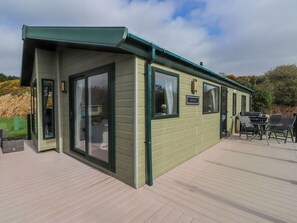 A green-roofed building with large windows, a deck, and a sign labeled 'BOSTON.' - The Stables (Pwllheli)
