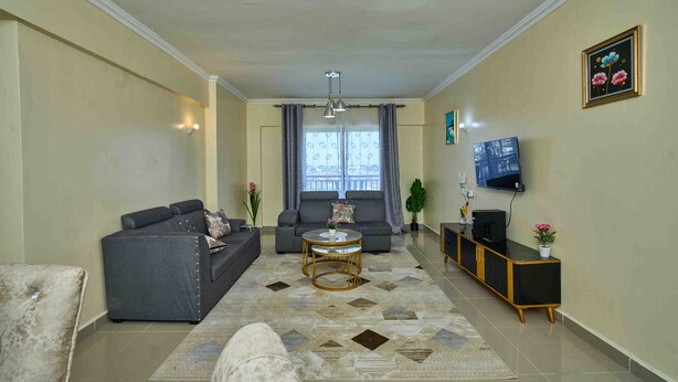 Una sala de estar con sofá, mesa de centro, televisor y mueble.