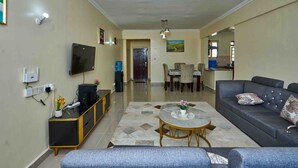 Una sala de estar con sofá, una mesa de centro, televisor y un comedor con sillas y mesa.