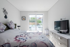 A bedroom with a bed, a TV, a dresser, a vase, and a window with a view. - Alvor Ria Retreat House (Alvor)