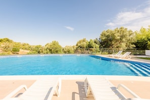 A swimming pool with clear blue water, surrounded by trees and a fence. - Alvor Ria Retreat House (Alvor)