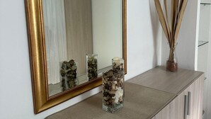 A mirror with a gold frame, a vase with dried reeds, and a container with stones on a wooden console. - Pigneto Metro Station, Line C, ground floor: spacious bedroom, kitchen, and bathroom. (Roma)