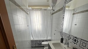 A bathroom with a toilet, sink, and shower curtain. - Pigneto Metro Station, Line C, ground floor: spacious bedroom, kitchen, and bathroom. (Roma)