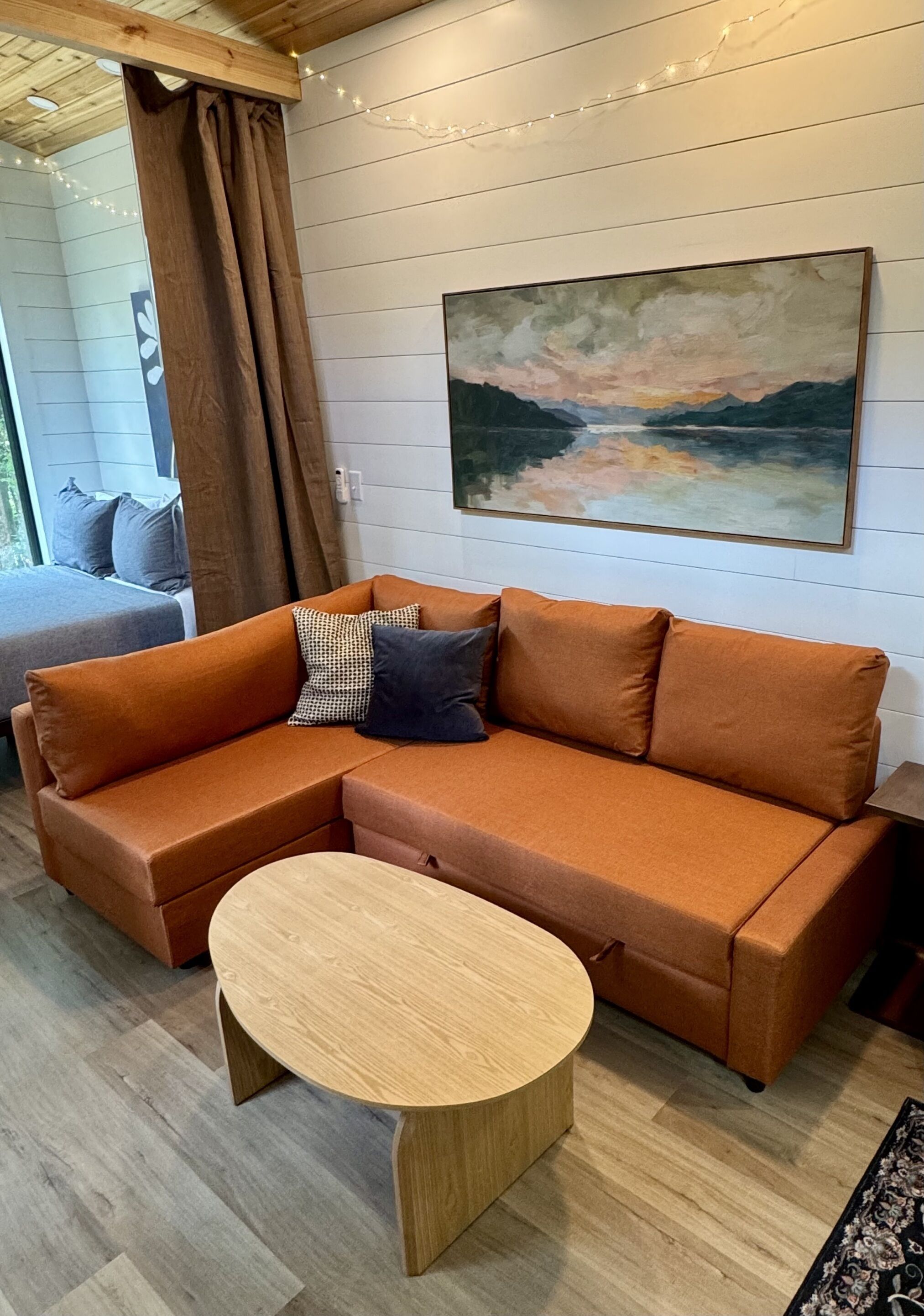 Ein modernes Wohnzimmer mit einer Eckcouch, einem runden Couchtisch und einem Gemälde an der Wand.