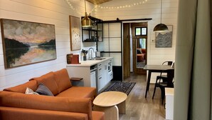 Ein modernes Interieur mit Holzboden, einer Couch, einem Esstisch und einer Küchenzeile.