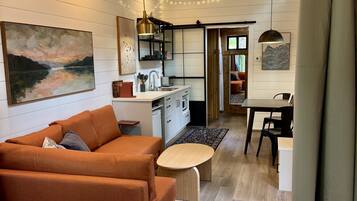 Ein modernes Interieur mit Holzboden, einer Couch, einem Esstisch und einer Küchenzeile.