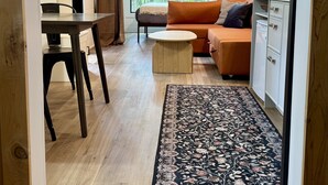 Ein modernes Wohnzimmer mit Holzboden, einer Couch, einem Couchtisch und einem Essbereich mit Tisch und Stühlen.