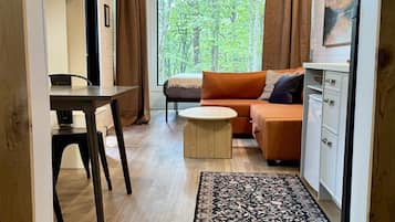 Ein modernes Wohnzimmer mit Holzboden, einer Couch, einem Couchtisch und einem Essbereich mit Tisch und Stühlen.