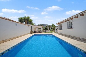 Ein rechteckiger Pool mit befliessten Rändern, umgeben von weißen Wänden mit dekorativen Fliesen und einem Flachdach.