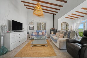 Uma sala de estar moderna com um sofá, uma mesa de centro de vidro e uma televisão.