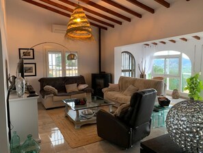Ein geräumiges Wohnzimmer mit Kamin, zwei Sofas, einem Glastisch und einem großen Fenster mit Blick.