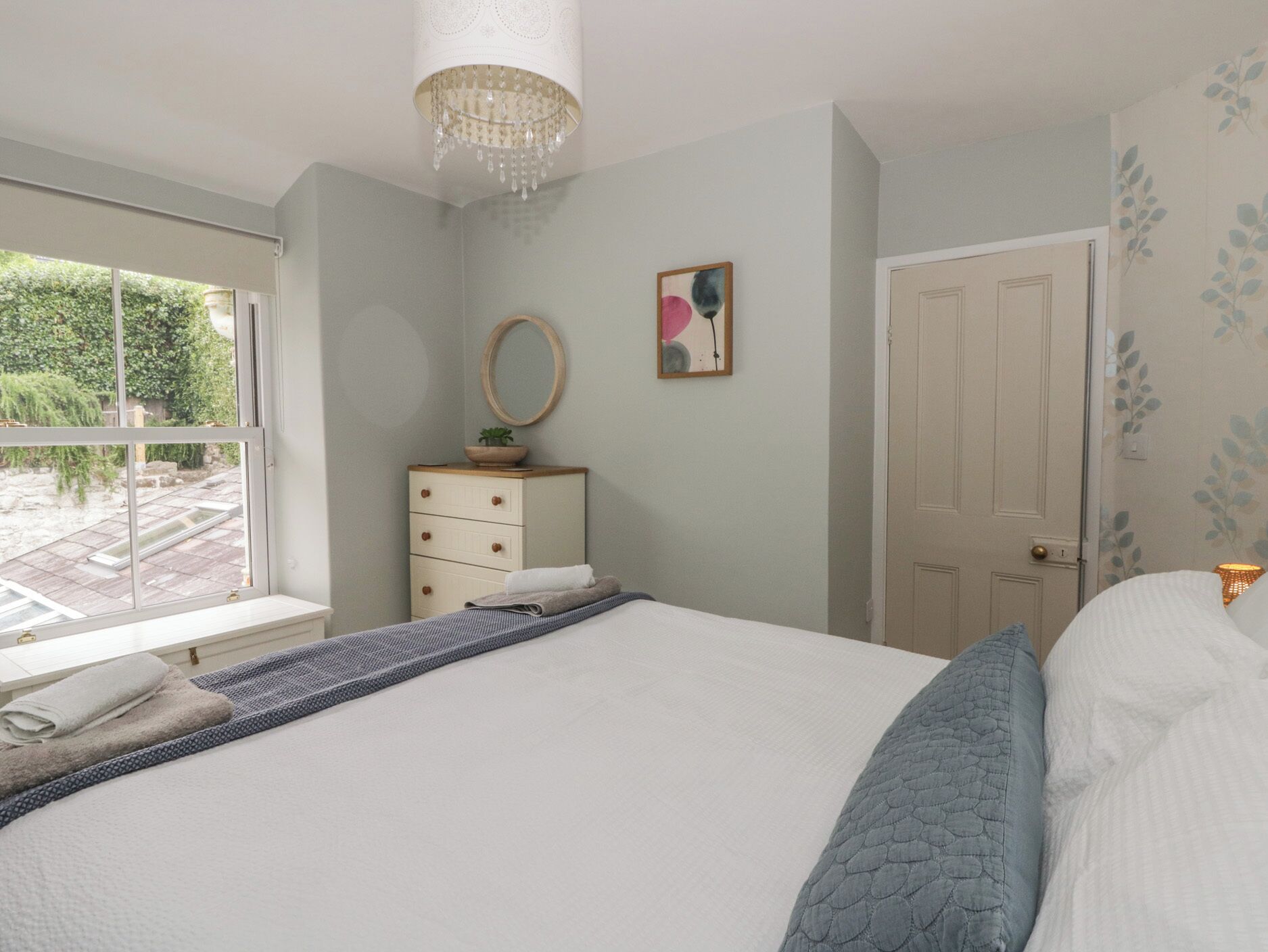 Un dormitorio con cama, cómoda, espejo, puerta y ventana.