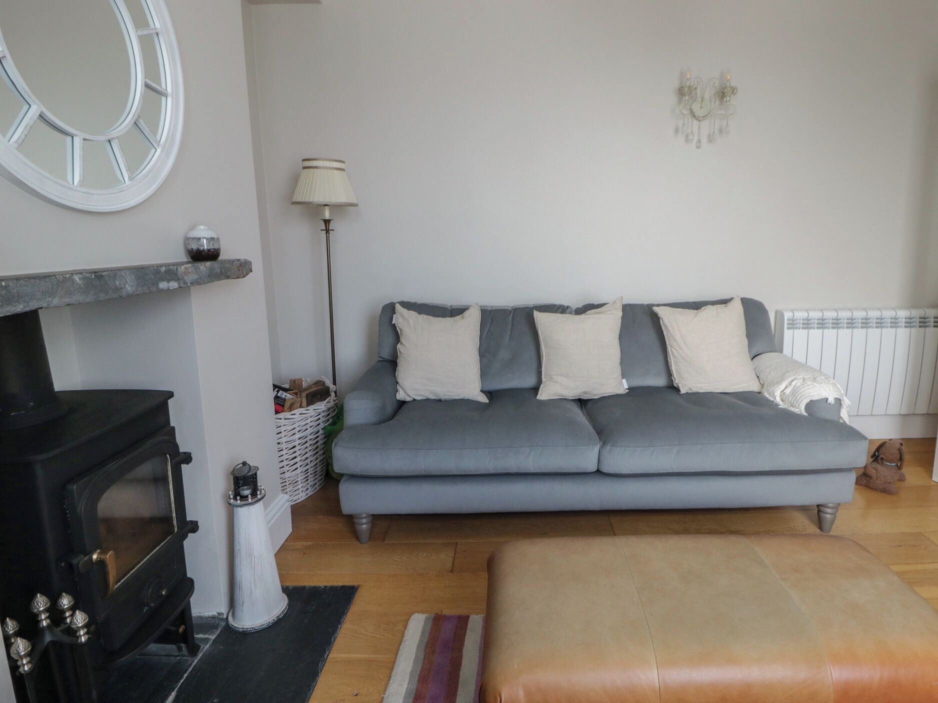 Una sala de estar con sofá, chimenea, lámpara y radiador.