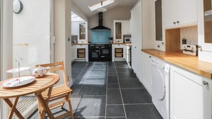 Cocina compacta con una isla central, armarios blancos, estufa negra y microondas integrado.