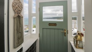 Una habitación con vista al mar, una puerta verde y un adorno de pared de mimbre.