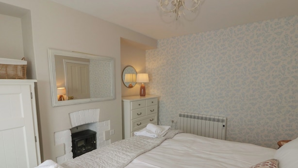 Un dormitorio con cama, cómoda, espejo, lámpara y radiador.