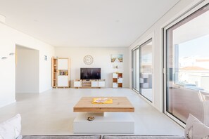 Ein modernes Wohnzimmer mit einem Flachbildfernseher, einem Couchtisch und einem großen Fenster.