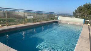 Una piscina en la azotea con agua azul cristalina, barandilla de vidrio y vistas al campo.