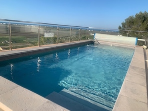 Ein Pool auf dem Dach mit klarem, blauem Wasser, einer Glasbrüstung und Blick auf die Landschaft.