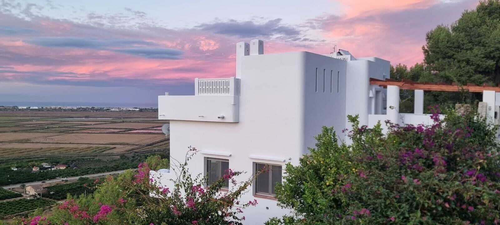 A modern white building with a flat roof, a small balcony, and a window.
