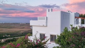 Un edificio moderno blanco con techo plano, un pequeño balcón y una ventana.