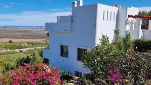 Un edificio blanco con vistas a un viñedo y un paisaje lejano.
