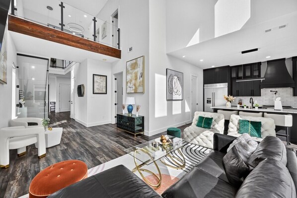 A modern living room with a sofa, coffee table, and a dining area with a kitchen in the background.