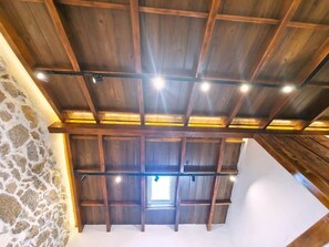 A high ceiling with wooden beams and recessed lighting.