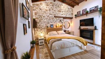 Un dormitorio con pared de piedra, cama, televisor y chimenea.