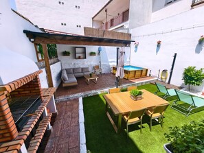 A patio with a barbecue, a wooden table, and a pool.
